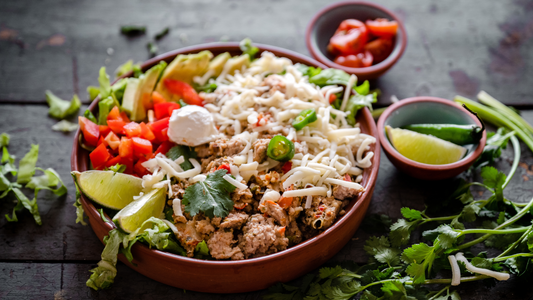 Picture of a rice bowl topped with salsa, cheese, fresh herbs, and lime wedges.