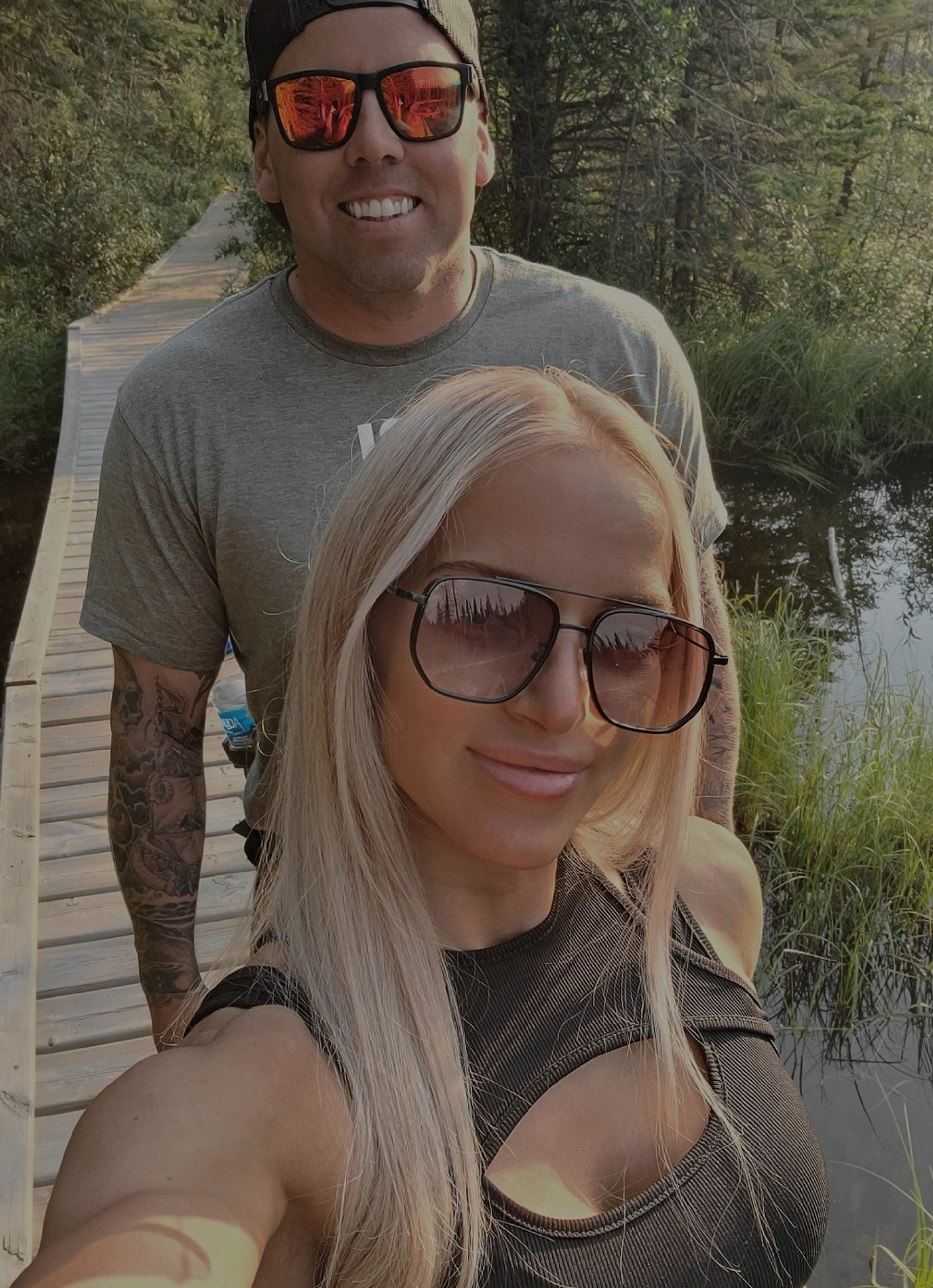 A picture of Healthy Devil founders Christina & Brendan, standing on a pier. Both are wearing sunglasses and smiling into the camera.