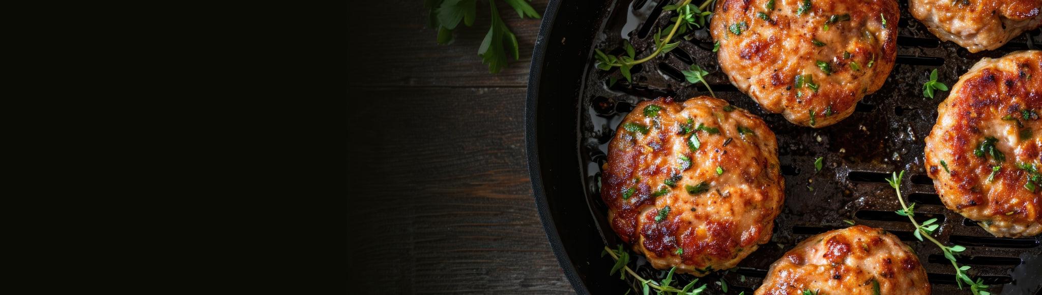 Chicken burger patties on a cast-iron grill pan, with fresh herbs, on a wooden table.